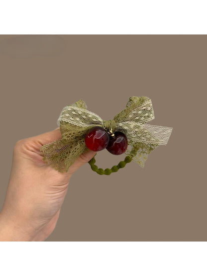 Green lace bow hair tie with intricate floral pattern on elastic band