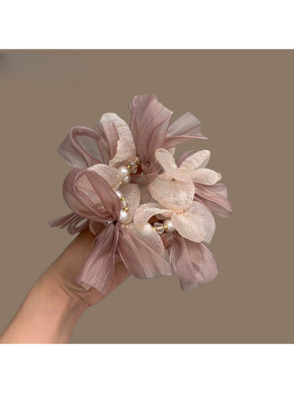Pink bow scrunchie worn on a wrist as a stylish accessory