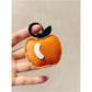 Red apple keychain resting on a white background with soft shadows