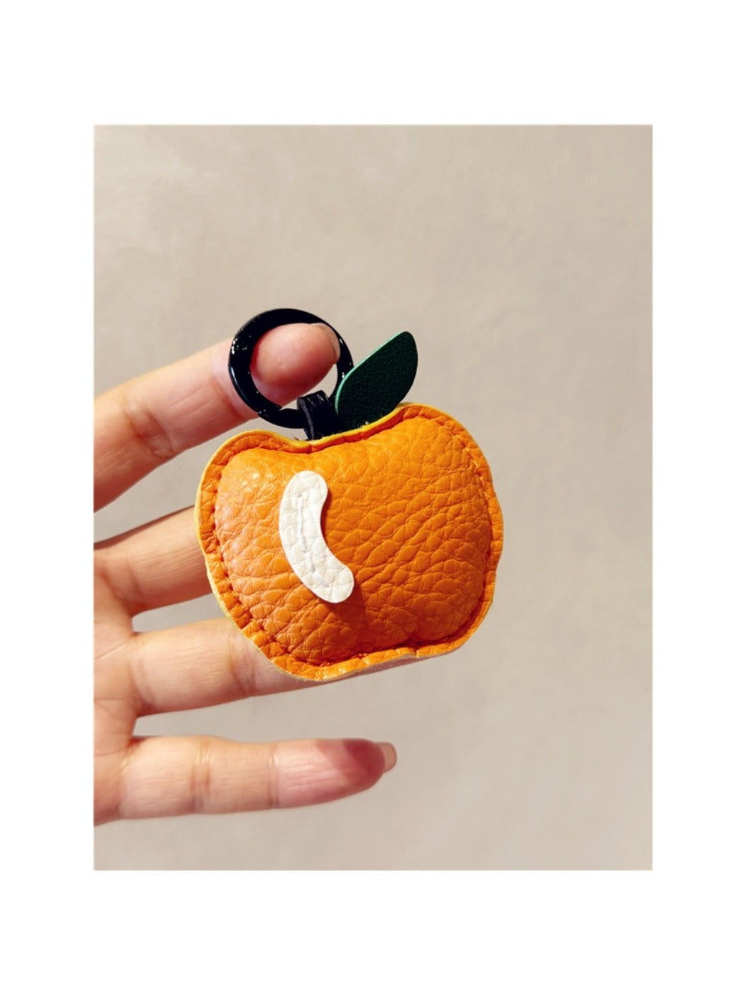 Red apple keychain resting on a white background with soft shadows