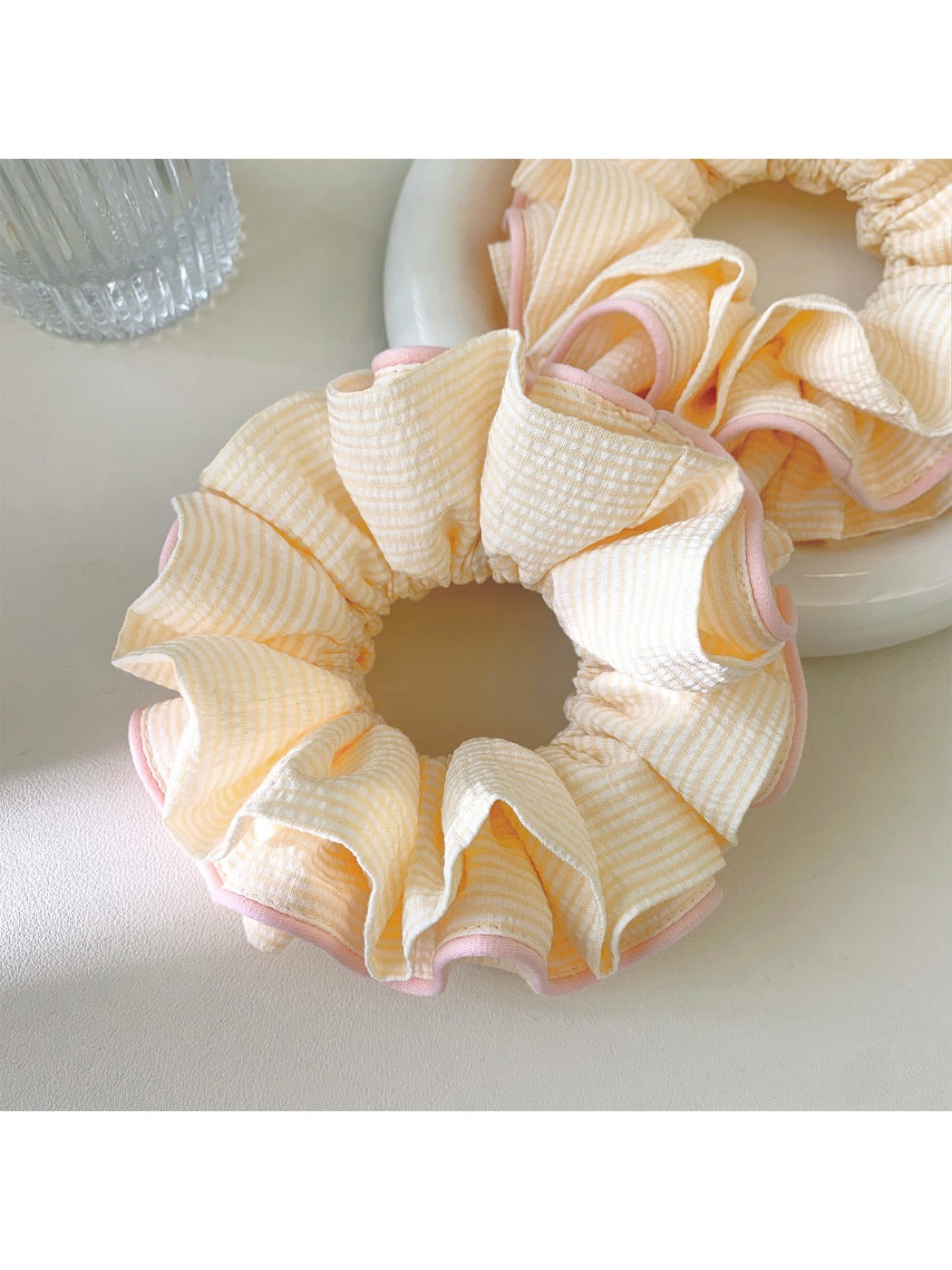 Pink ruffle beige scrunchie worn on a model's wrist