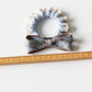Multiple bow hair ties in pastel colors displayed on a textured fabric