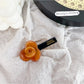 Beau hair clip placed on a wooden surface with soft natural lighting