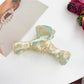 Beau bow shaped claw clip holding a bun hairstyle from the back