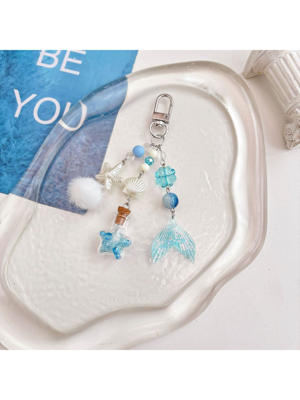 Blue drift bottle keychain hanging from a backpack zipper pull