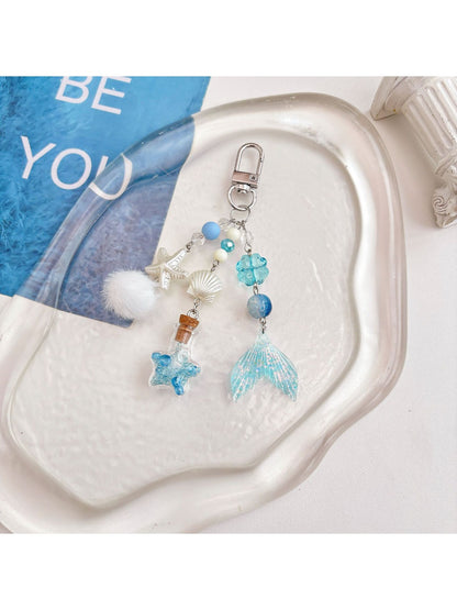 Blue drift bottle keychain hanging from a backpack zipper pull