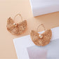 Close-up of gold hooks attached to vintage fan shaped raffia earrings