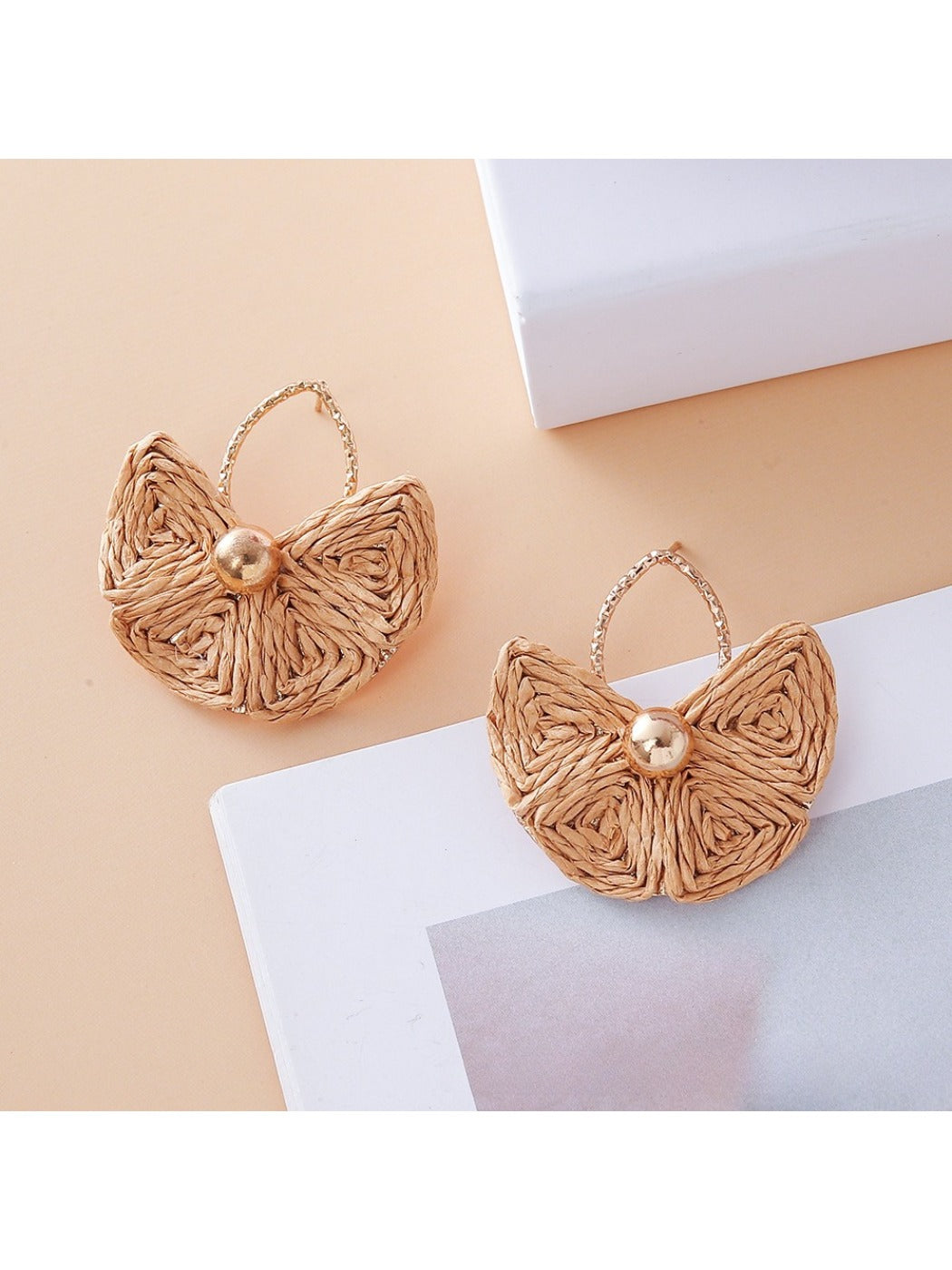 Close-up of gold hooks attached to vintage fan shaped raffia earrings