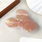 Beau bow hair claw clip resting on textured fabric surface