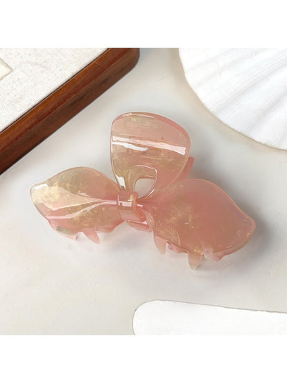 Beau bow hair claw clip resting on textured fabric surface