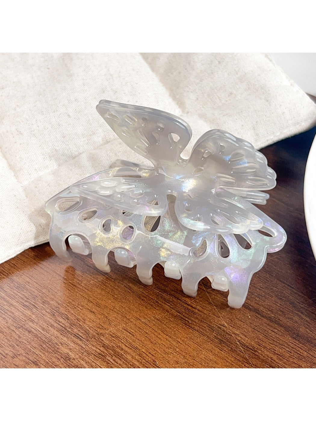Beau butterfly hair claw clip in pastel pink placed on a wooden surface