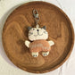 Silver cat charm keychain resting on a wooden table with natural light