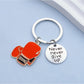 Alloy boxing glove keychain attached to a set of keys on a wooden surface