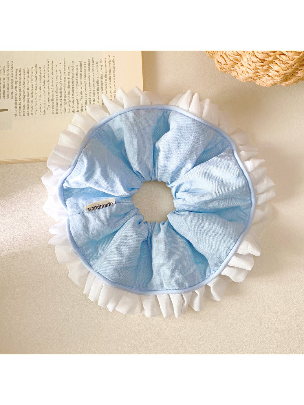 Blue ruffle scrunchie wrapped around a ponytail in brown hair