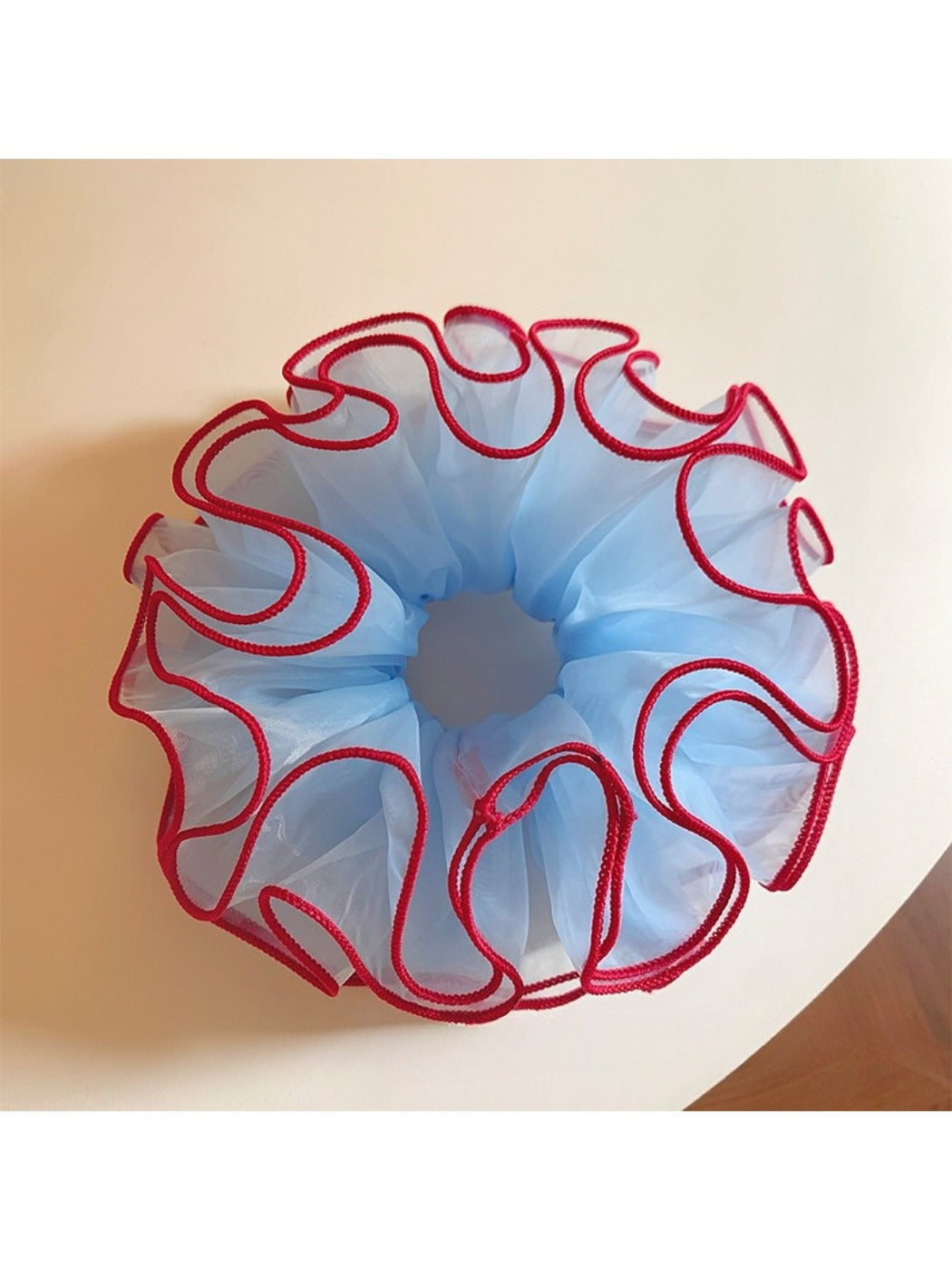 Blue tulle scrunchie with red trim worn on a wrist