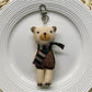 Fabric bear cub bag charm keychain hanging from a backpack zipper pull