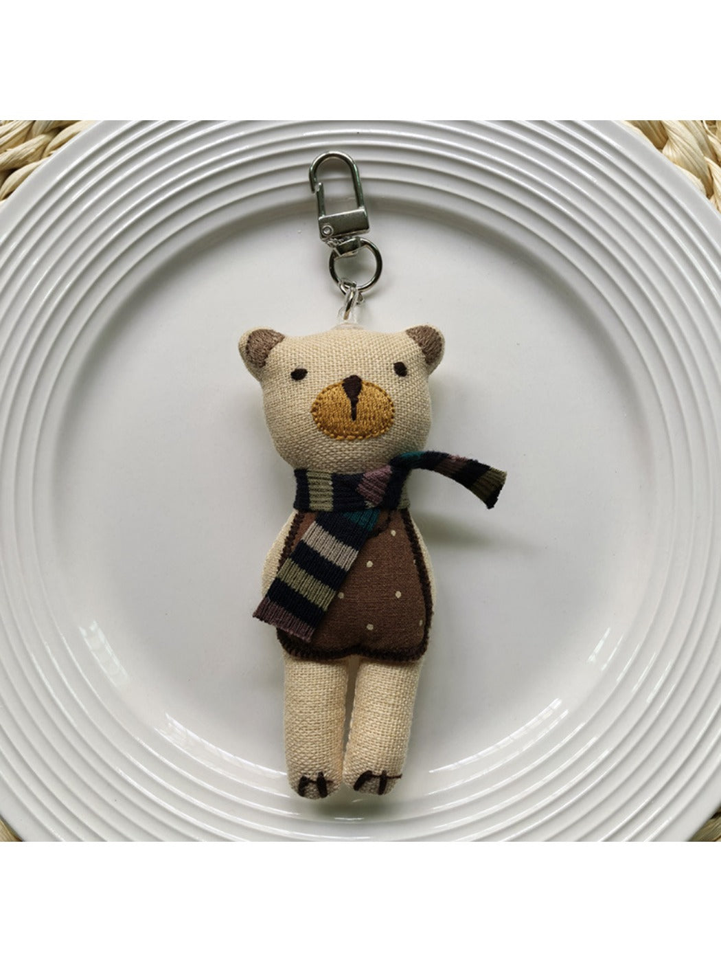 Fabric bear cub bag charm keychain hanging from a backpack zipper pull