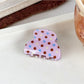 Beau crescent shaped pink claw clip with white polka dots isolated on a plain background