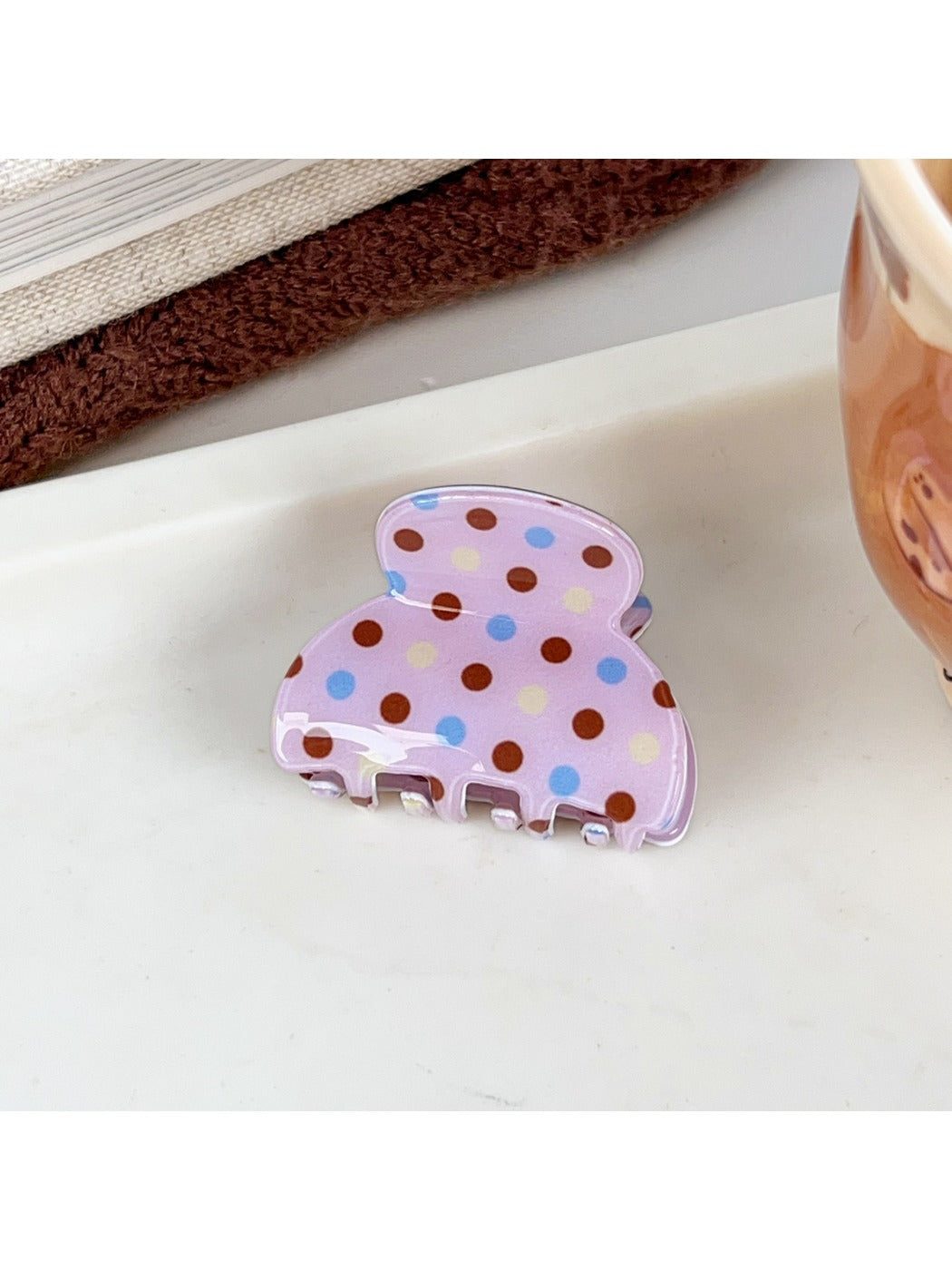 Beau crescent shaped pink claw clip with white polka dots isolated on a plain background