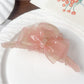 Beau double layer bow hair claw clip in light pink held in hand for size
