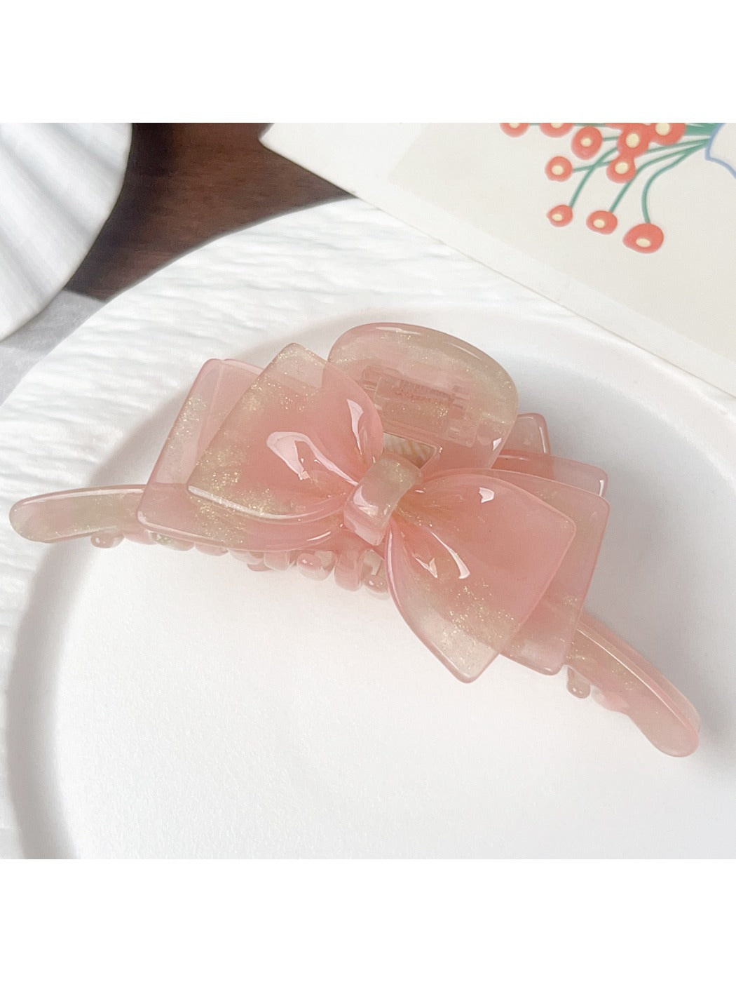 Beau double layer bow hair claw clip in light pink held in hand for size