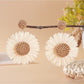 Flat lay of vintage raffia sunflower earrings with natural elements like dried flowers