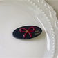Top view of beige oval butterfly hair clip on a flat surface