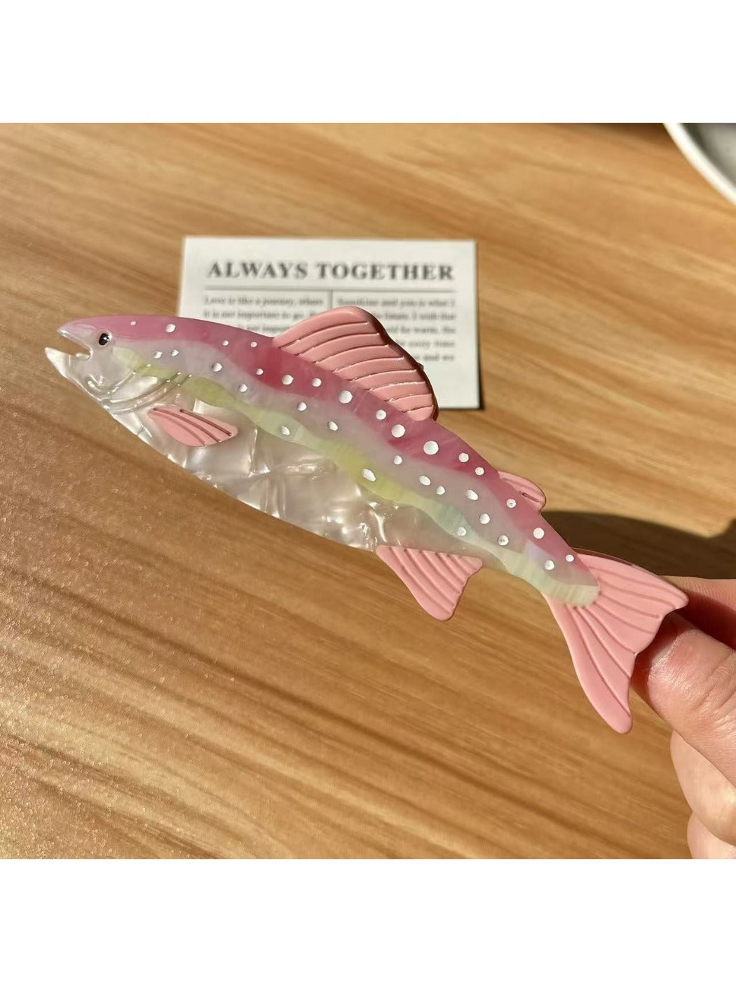 Beau elegant salmon shaped hair claw clip placed on wooden surface