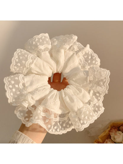 White ruffled scrunchie holding a ponytail in a natural hair setting