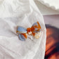 Beau delicate bow hair clip resting on a white fabric background