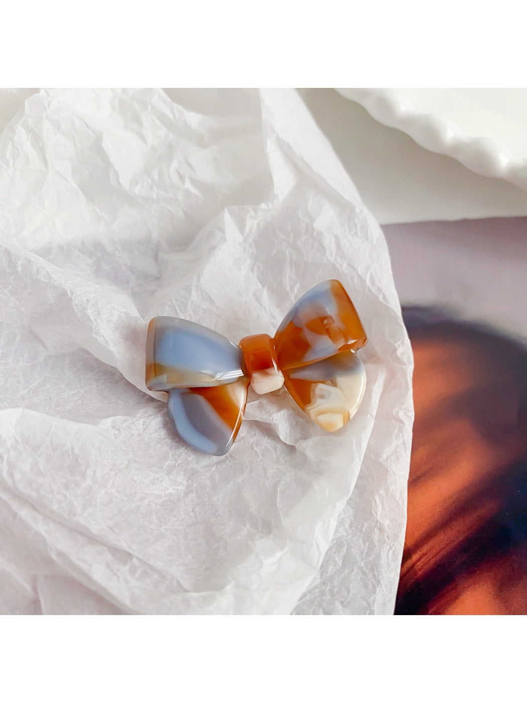 Beau delicate bow hair clip resting on a white fabric background