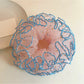 Pink ruffled scrunchie styled on a wrist with layered fabric design
