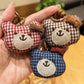 Bear charm keychain hanging from a backpack zipper in natural light