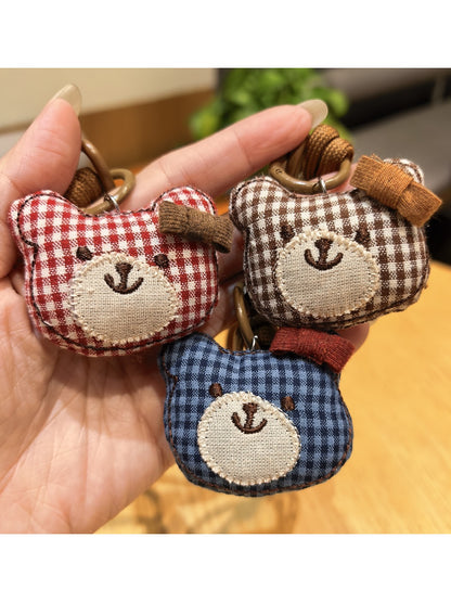 Bear charm keychain hanging from a backpack zipper in natural light