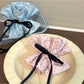 Close-up of Gifty sweet polka dot bow scrunchie in soft pink fabric with white dots