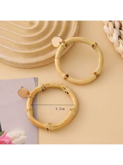 Earedge rattan round hollow earrings displayed on a wooden surface