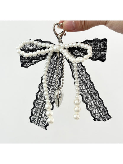 Lace bow keychain hanging from a handbag strap in natural lighting