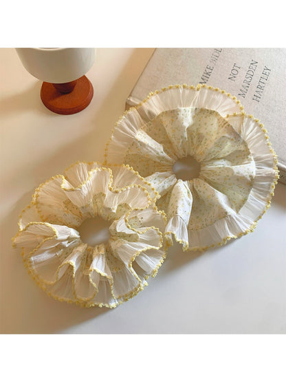 Yellow pleated scrunchie with floral print on white background