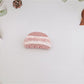 Beau claw clip placed on a wooden surface emphasizing marble design