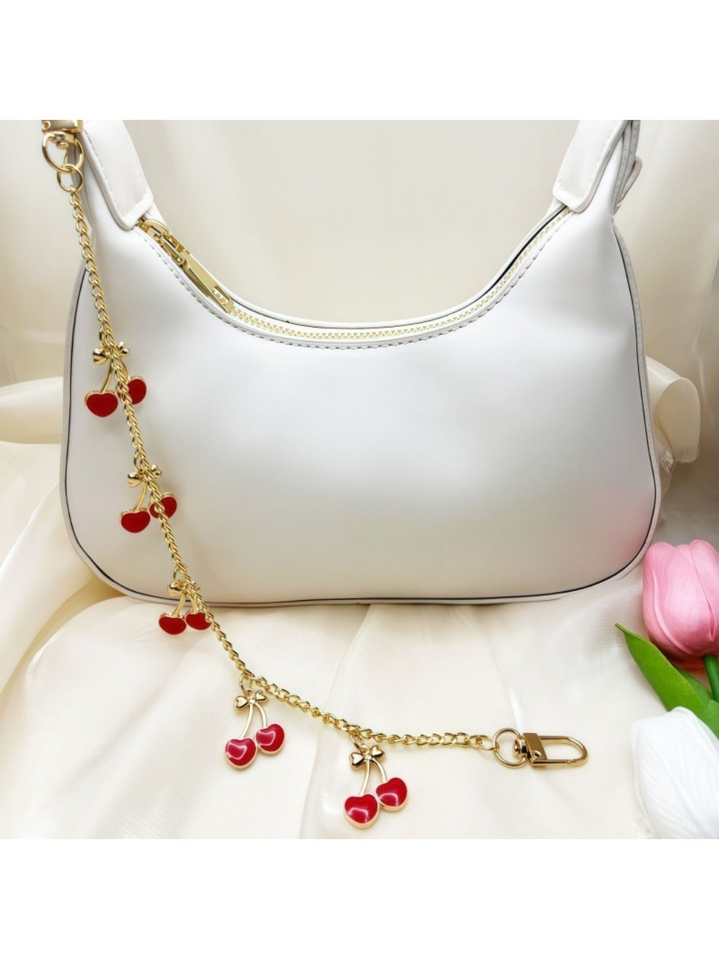 Close-up of the cherry bag charm showing smooth red enamel and green leaf detail
