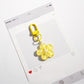 Flower-shaped keychain with a shiny metal keyring on a plain surface