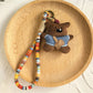 Keypus fabric doll keychain hanging from a purse handle