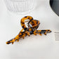 Beau colorful floral hair claw clip resting on fabric with floral print