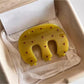 Yellow Beau claw hair clip with white polka dots on a white background
