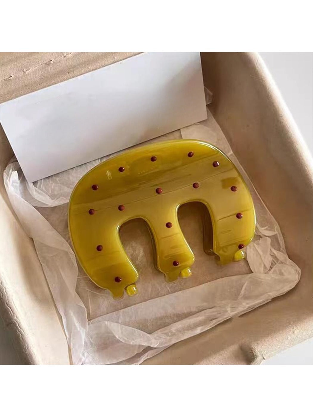 Yellow Beau claw hair clip with white polka dots on a white background