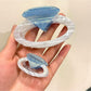 Beau ring shape claw clip resting on white surface, top view