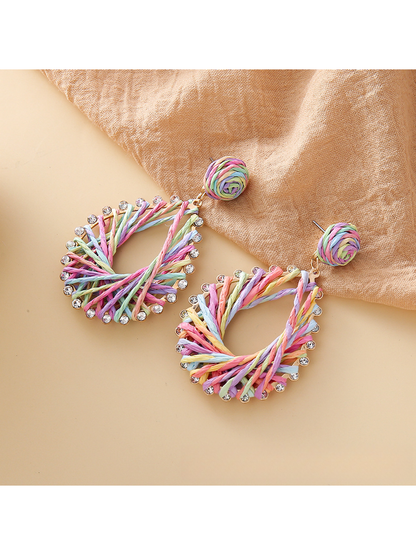 Side view of raffia drop earring showing woven geometric design