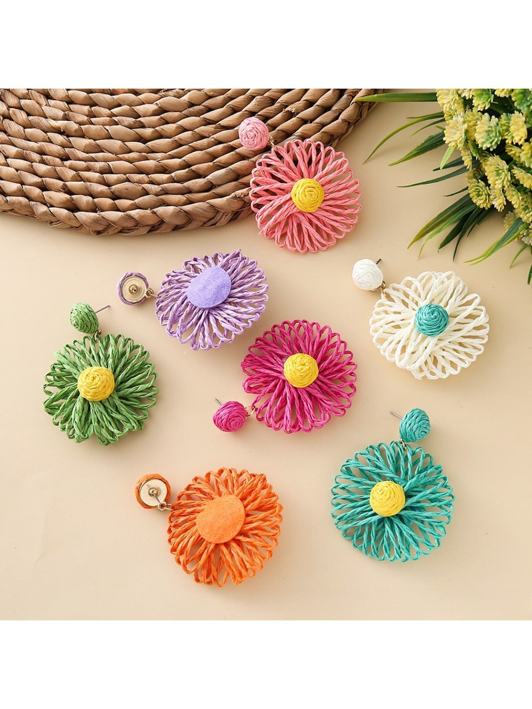 Pair of raffia sunflower earrings displayed on a white background