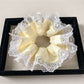 Yellow and white fabric hair scrunchie displayed flat on a wooden surface