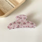 Beau hair claw clip placed on a wooden surface showing floral pattern